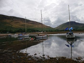 Sailboats moored on lake against sky