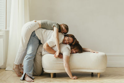 Happy mother having fun with daughters on sofa at home