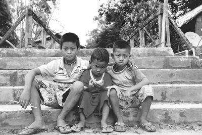 Portrait of brothers sitting on steps in park