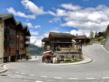 People on road by buildings against sky