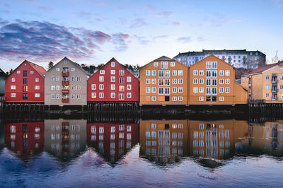 Buildings by river against sky