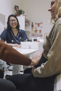 Hand of man touching stomach of pregnant woman in clinic