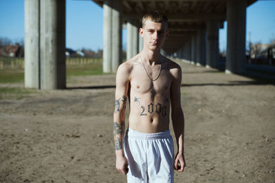 Portrait of young shirtless man standing outdoors