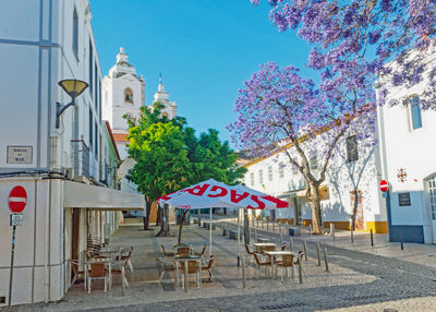 Empty chairs and tables against buildings in city