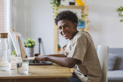 Happy teenage boy using laptop at home