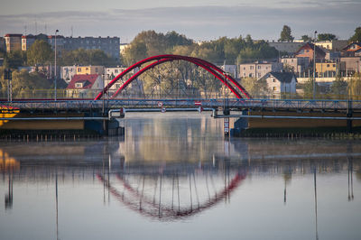 Bridge over river by buildings against sky in city