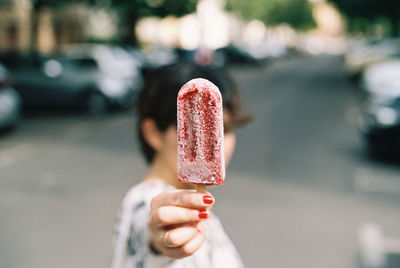 Woman holding flavored ice while standing on street