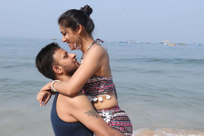 Side view of couple at beach against sky