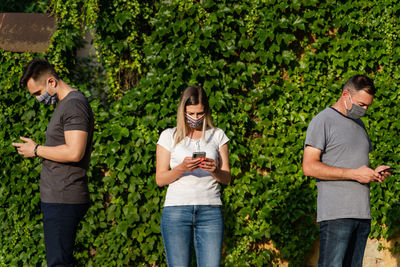 Full length of friends standing on mobile phone