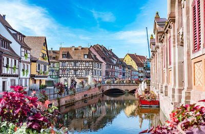 Canal amidst buildings in city against sky