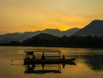 Silhouette boat in lake against sky during sunset