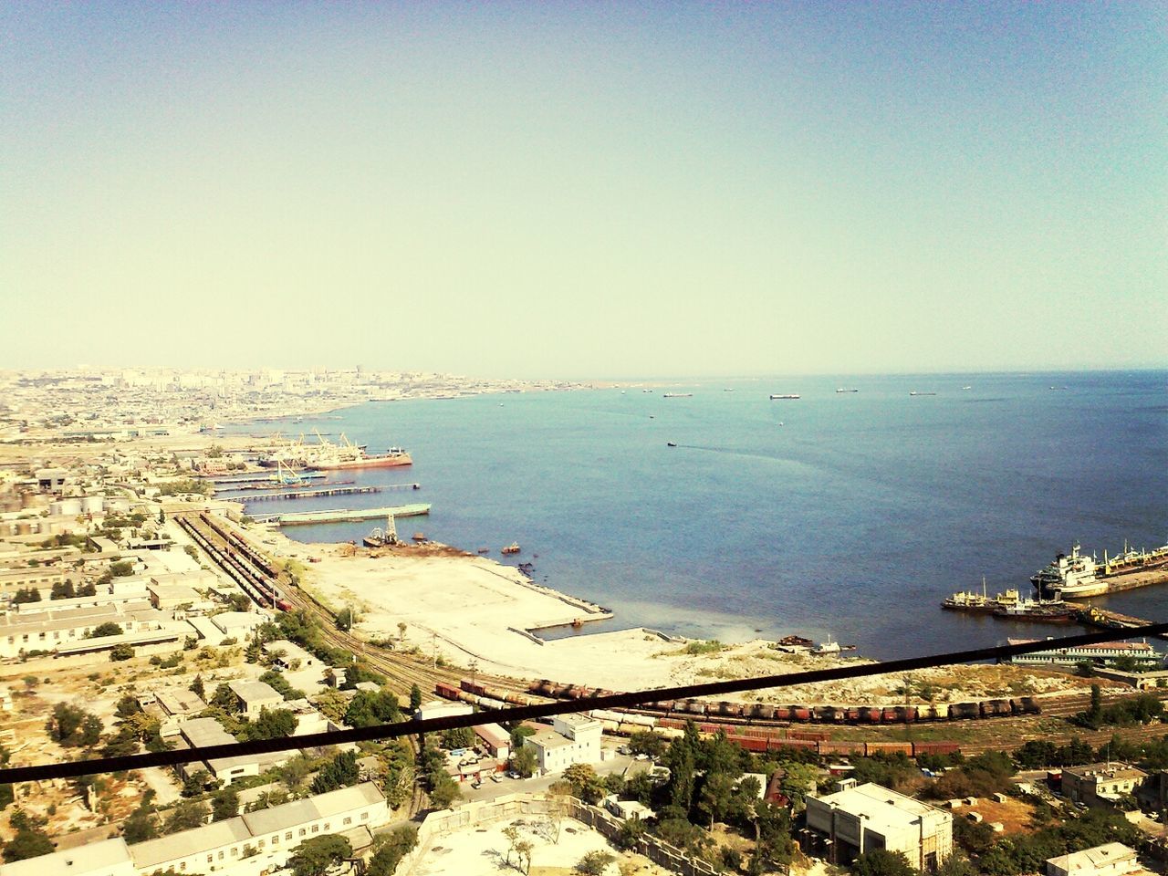 sea, water, clear sky, horizon over water, copy space, built structure, architecture, high angle view, building exterior, beach, nautical vessel, blue, transportation, shore, scenics, nature, tranquility, tranquil scene, day, coastline