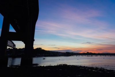 Bridge over river against sky during sunset
