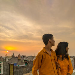 Friends standing against orange sky during sunset