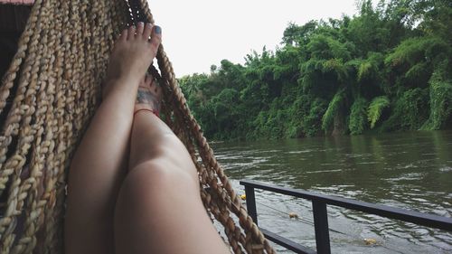 Low section of woman in hammock by lake