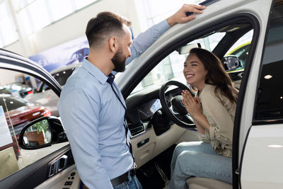 Happy customer thanking salesman in car showroom