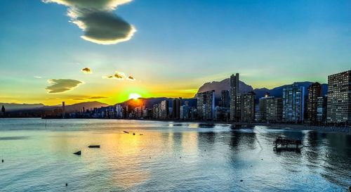 Scenic view of sea and buildings against sky during sunset