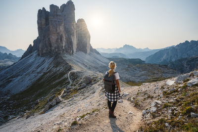 Rear view of man standing on rock against sky