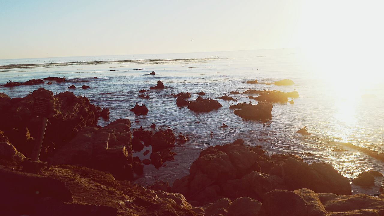 water, clear sky, scenics, sea, tranquility, tranquil scene, beauty in nature, nature, sky, horizon over water, rock - object, sunlight, idyllic, copy space, reflection, sunset, outdoors, no people, non-urban scene, beach