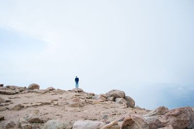 Rear view of man standing on mountain during foggy weather