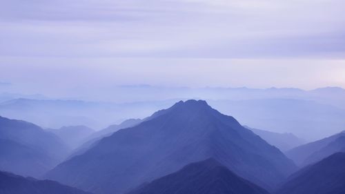 Scenic view of mountains against cloudy sky during foggy weather
