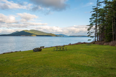 Landscape of grassy knoll, picnic table, trees, ocean and islands in anacortes, washington