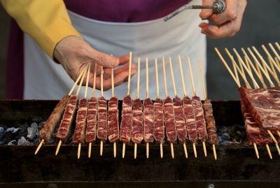 Midsection of man preparing food on barbecue grill