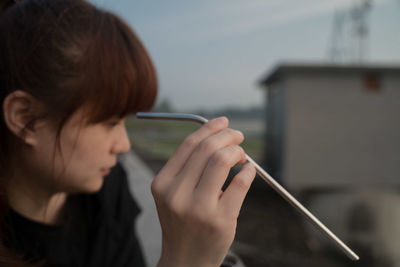 Close-up portrait of woman holding reusable stainless steel straw