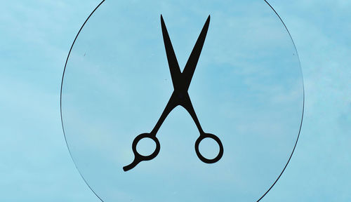 Low angle view of scissors against sky