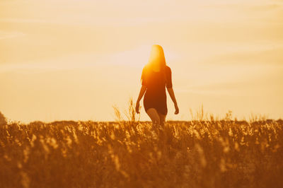 Beautiful women walking through field against clear sky