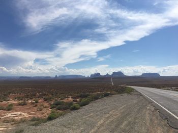 Road by landscape against blue sky