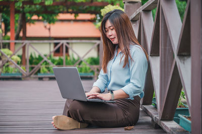 Young woman using mobile phone while sitting outdoors