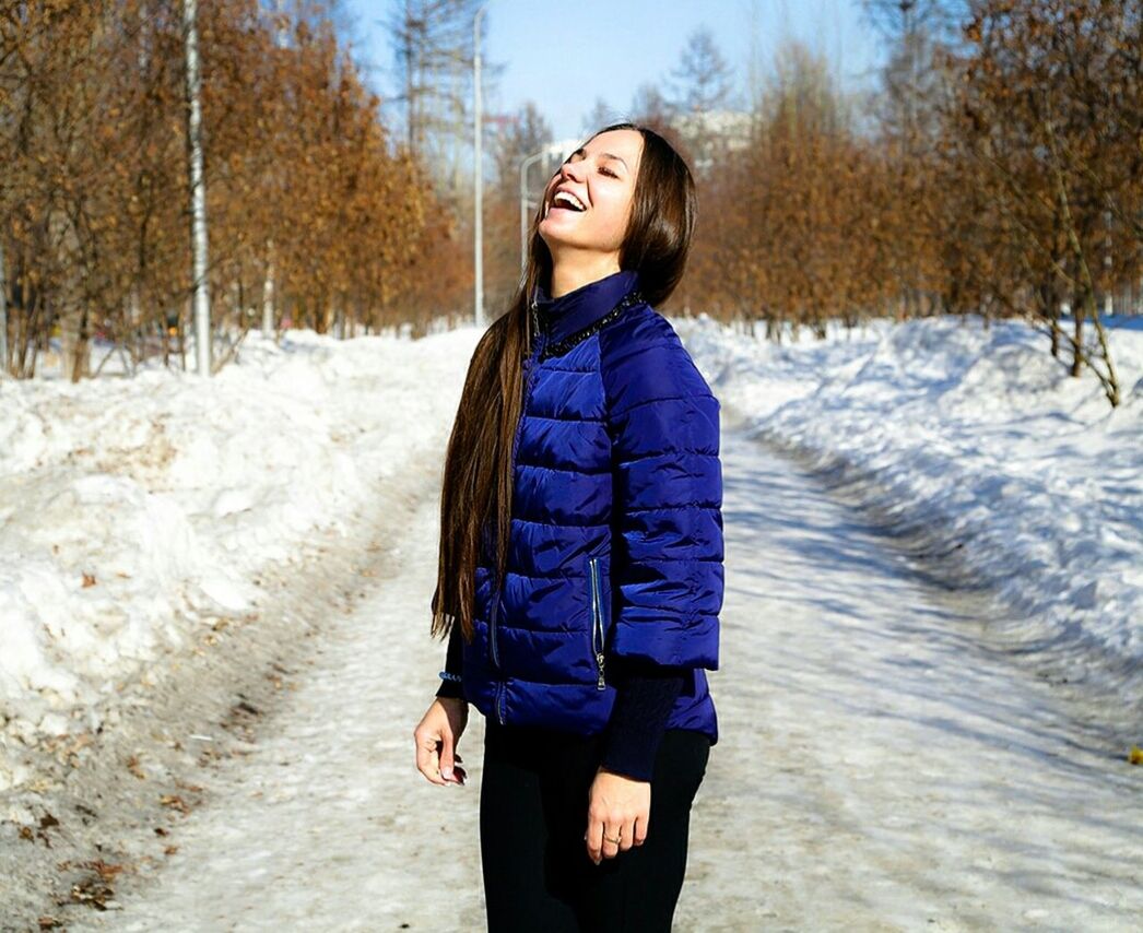 YOUNG WOMAN IN WINTER STANDING AGAINST SNOW