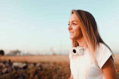 Portrait of smiling woman standing on field against sky