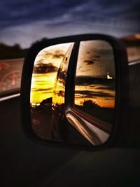 Reflection of car on side-view mirror at sunset