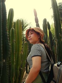 Young woman standing by succulent plant against sky