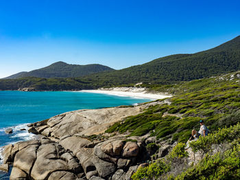 Scenic view of sea and mountains against clear blue sky