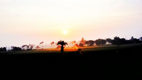 Silhouette of people on landscape at sunset