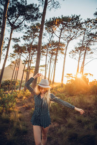 Woman standing against trees during sunset