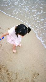 High angle view of girl playing on sand at beach