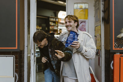 Happy gay couple laughing while leaving from supermarket