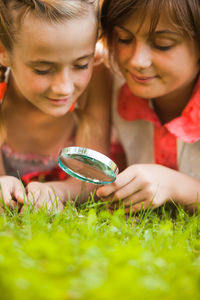 Boy and girl looking through magnifying glass on grass