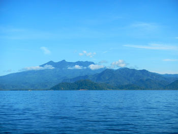 Scenic view of sea and mountains against blue sky