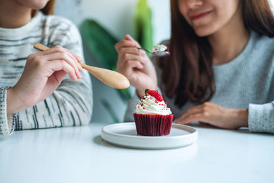 Two women enjoyed eating red velvet cup cake together