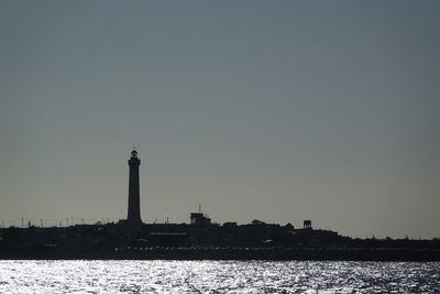 Lighthouse in city against clear sky