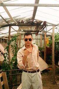 Portrait of young man standing in greenhouse
