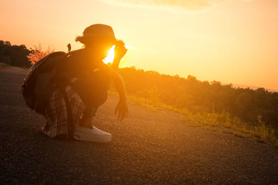 Man and woman on road against sky during sunset