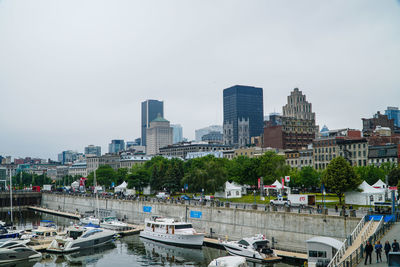 Boats moored at river with city in background