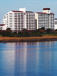 Buildings by river against blue sky