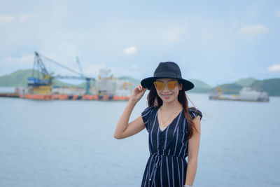 Smiling young woman standing by sea